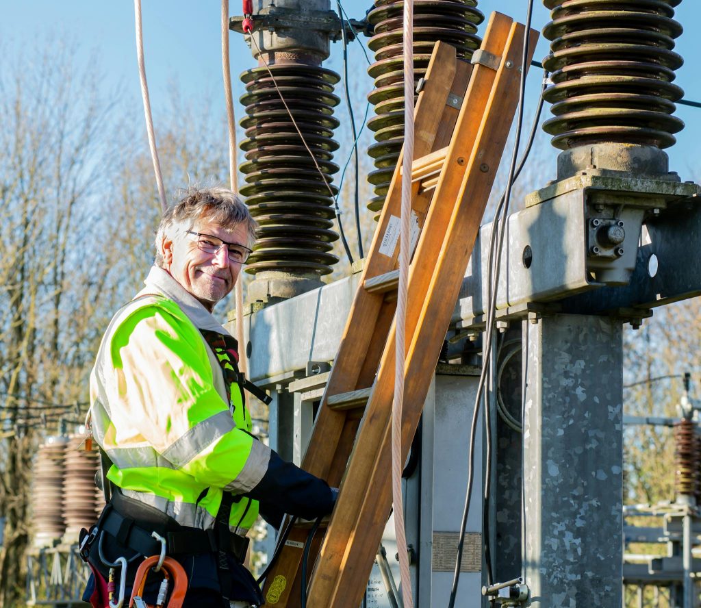 Electrician climbing ladder at power substation, ensuring safety in maintenance.